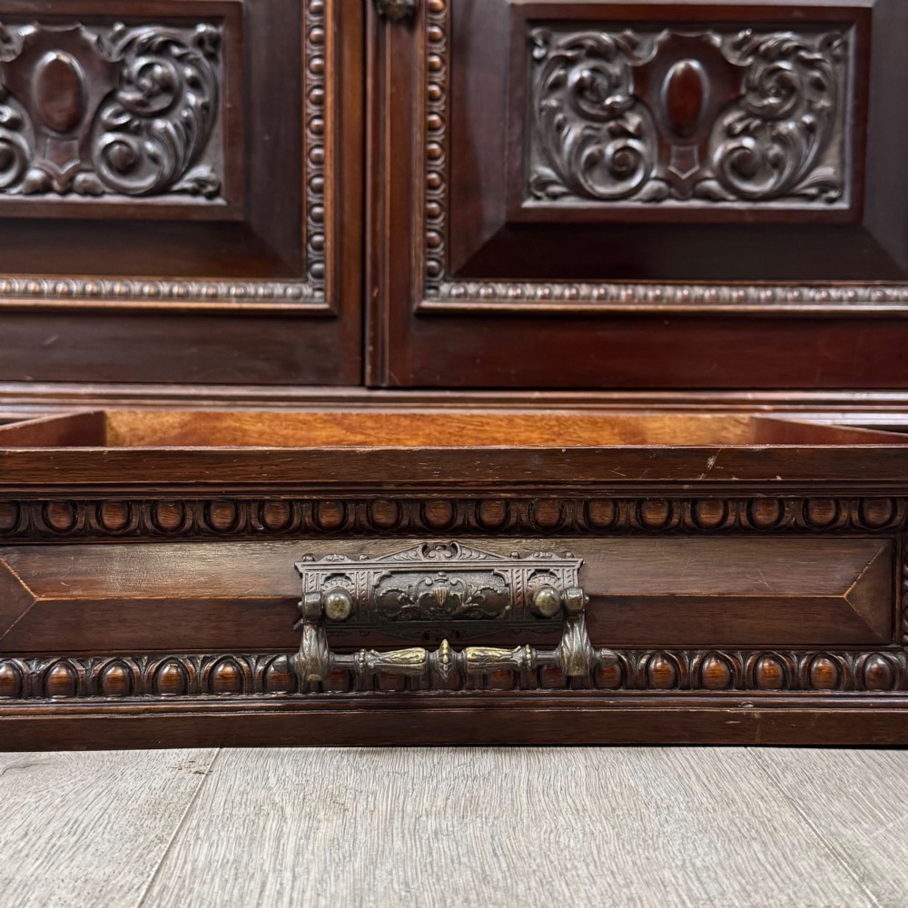 A nineteenth-century dark mahogany glazed bookcase featuring a carved swan neck pediment, twin arched glass upper doors, and a lower two-door cabinet with carved panels. View XII