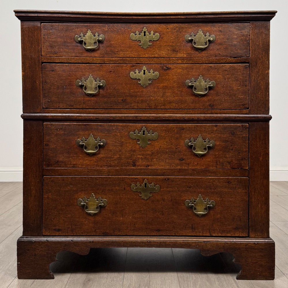 A seventeenth-century William and Mary oak chest of drawers featuring four drawers with brass escutcheons and drop handles raised on bracket feet.