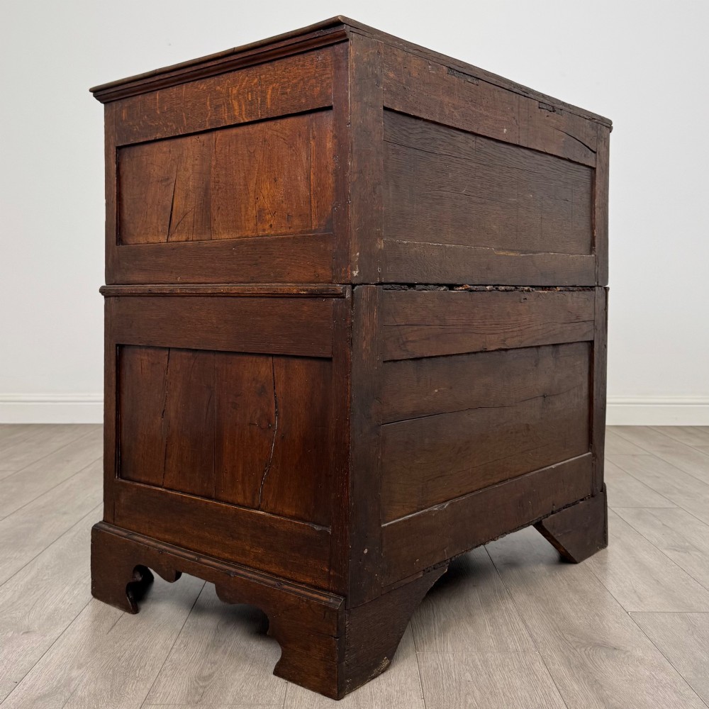 A seventeenth-century William and Mary oak chest of drawers featuring four drawers with brass escutcheons and drop handles raised on bracket feet. View IV
