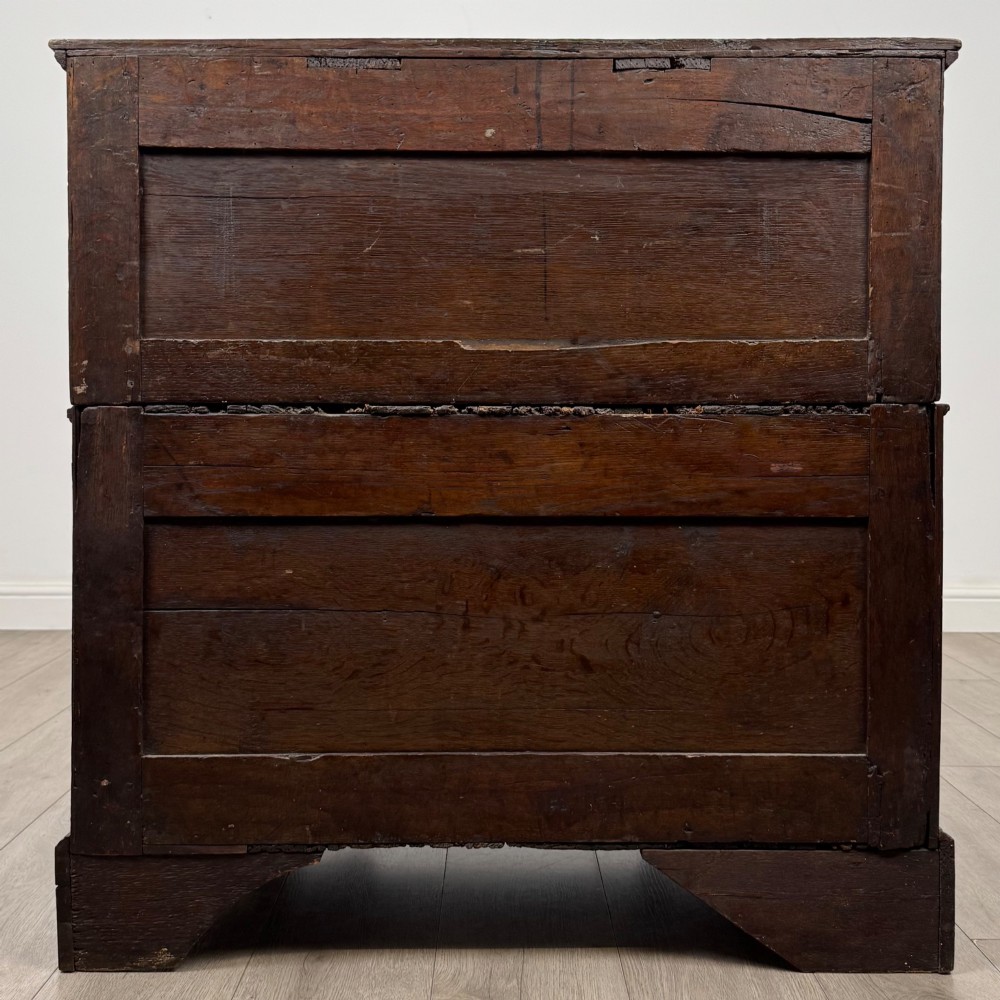 A seventeenth-century William and Mary oak chest of drawers featuring four drawers with brass escutcheons and drop handles raised on bracket feet. View V