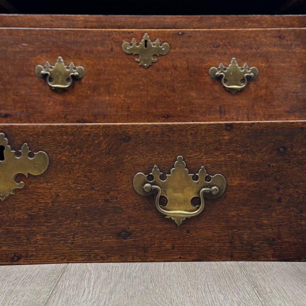 A seventeenth-century William and Mary oak chest of drawers featuring four drawers with brass escutcheons and drop handles raised on bracket feet. View XI