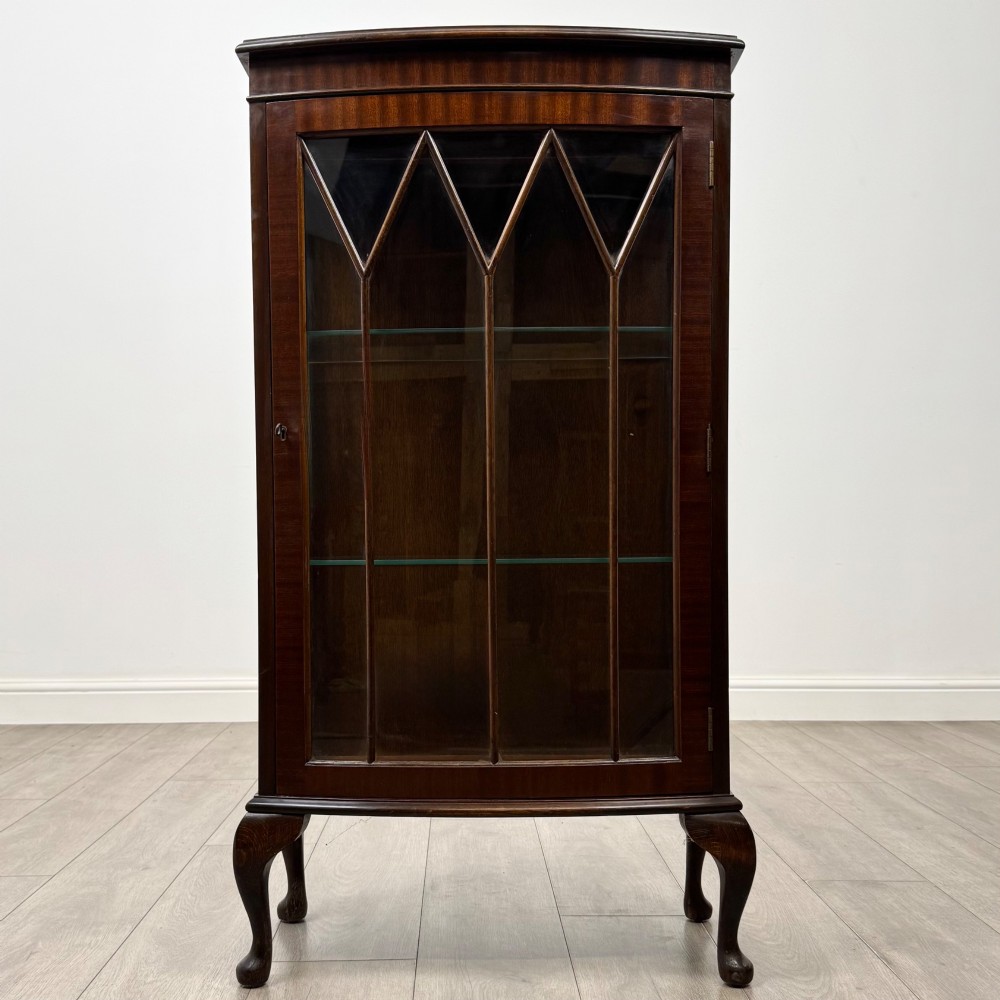 An antique mahogany display cabinet featuring a single door with geometric astragal glazing bars, glass shelves, and cabriole legs.
