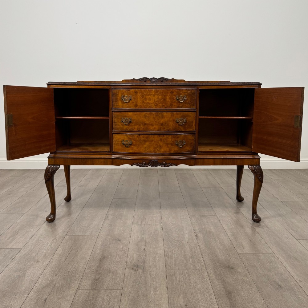 A 20th-century burr walnut sideboard featuring three central bowfront drawers flanked by cupboard doors, supported on carved cabriole legs. View II