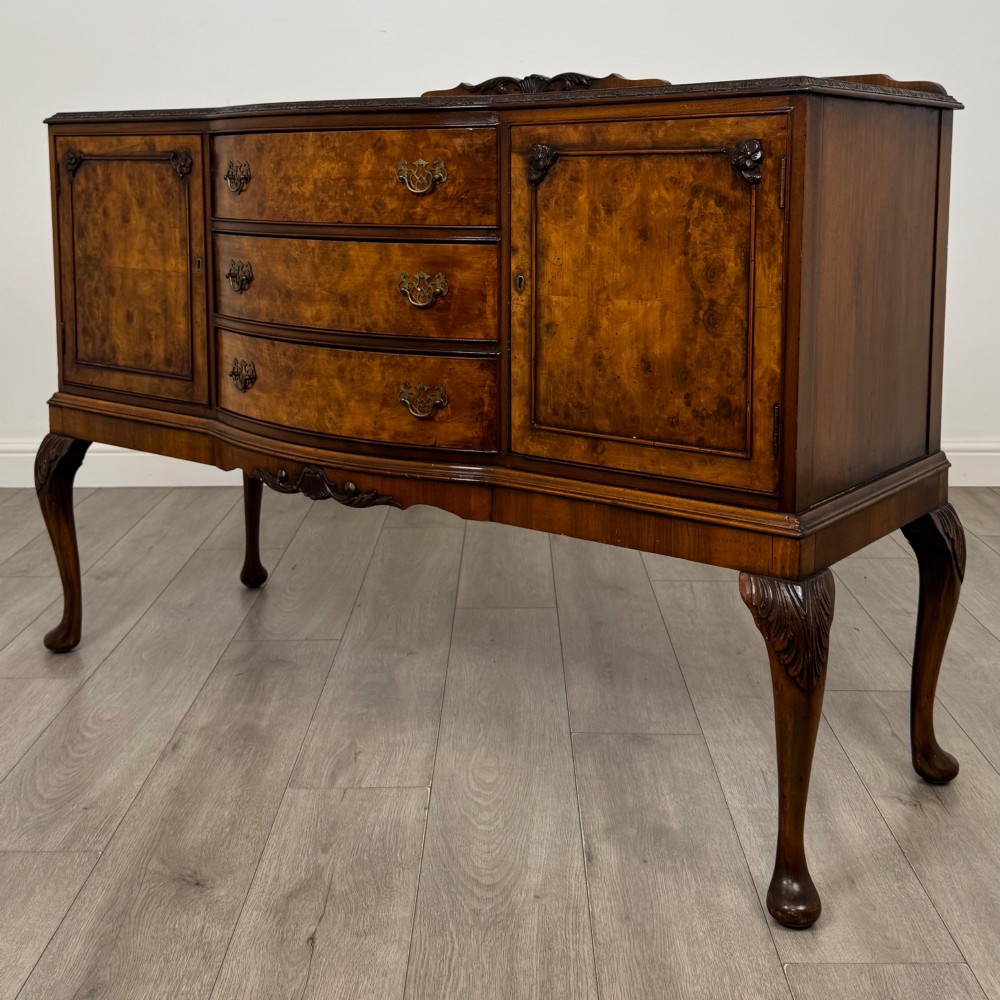 A 20th-century burr walnut sideboard featuring three central bowfront drawers flanked by cupboard doors, supported on carved cabriole legs. View III