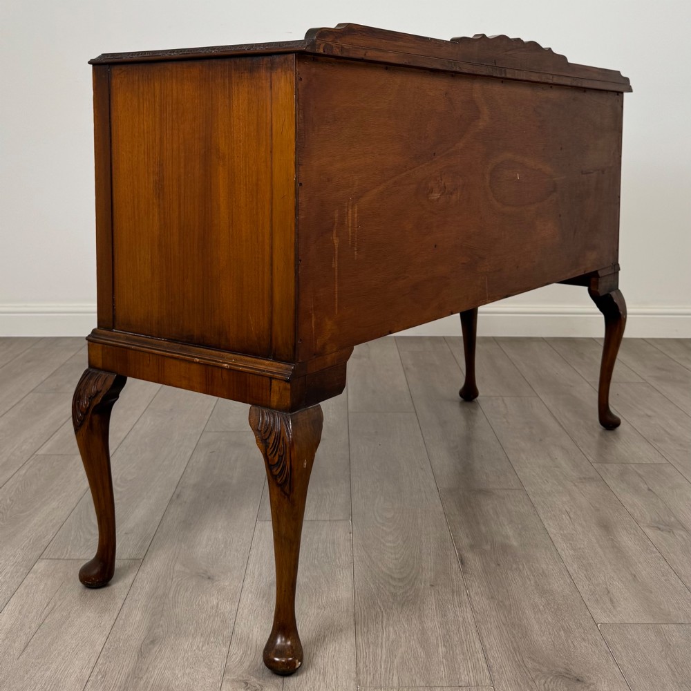 A 20th-century burr walnut sideboard featuring three central bowfront drawers flanked by cupboard doors, supported on carved cabriole legs. View V