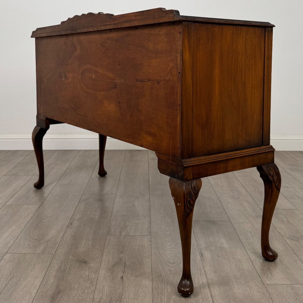 A 20th-century burr walnut sideboard featuring three central bowfront drawers flanked by cupboard doors, supported on carved cabriole legs. View VII