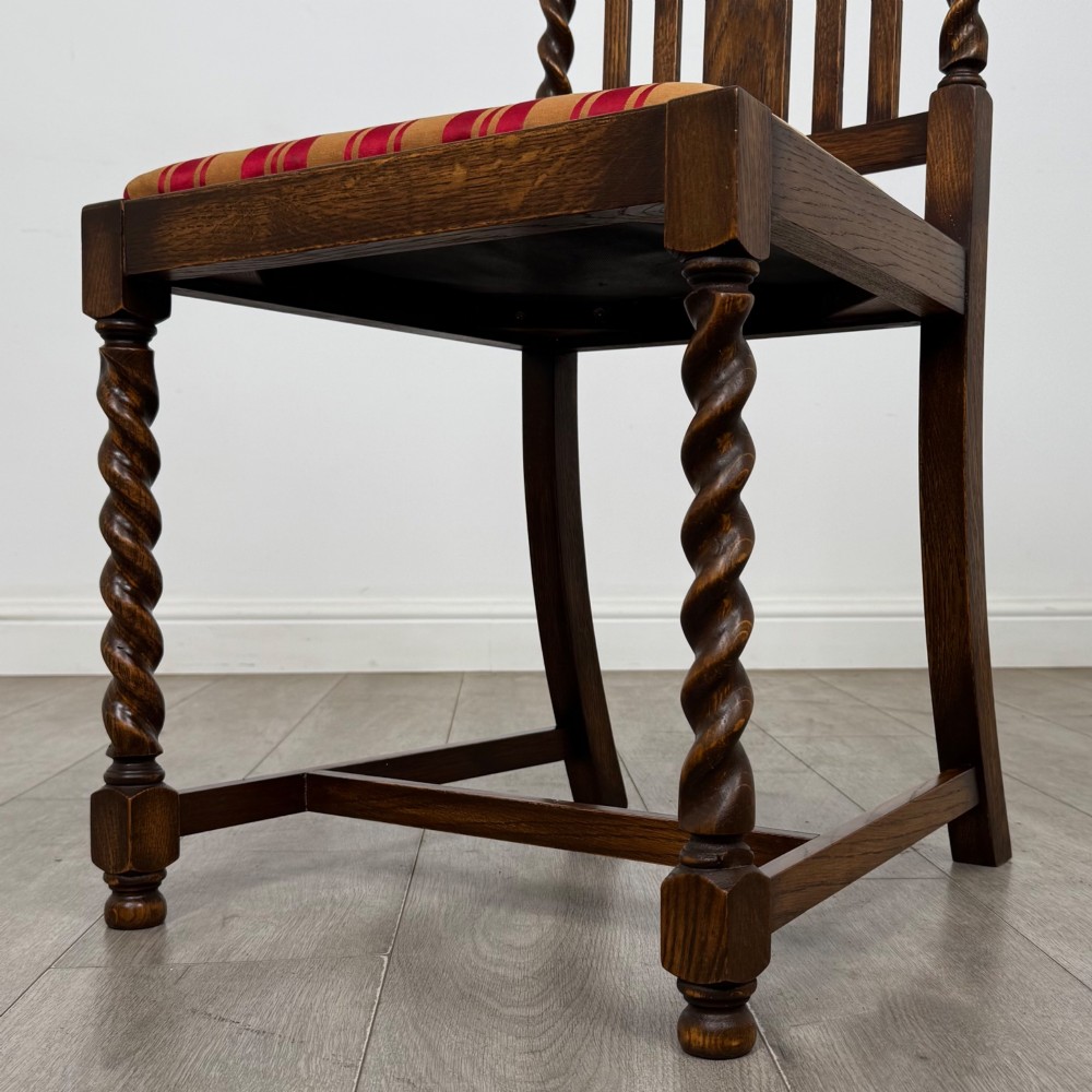 A set of four dark oak dining chairs featuring slatted backrests, barley twist front legs, and red and gold striped upholstered seat pads. View V