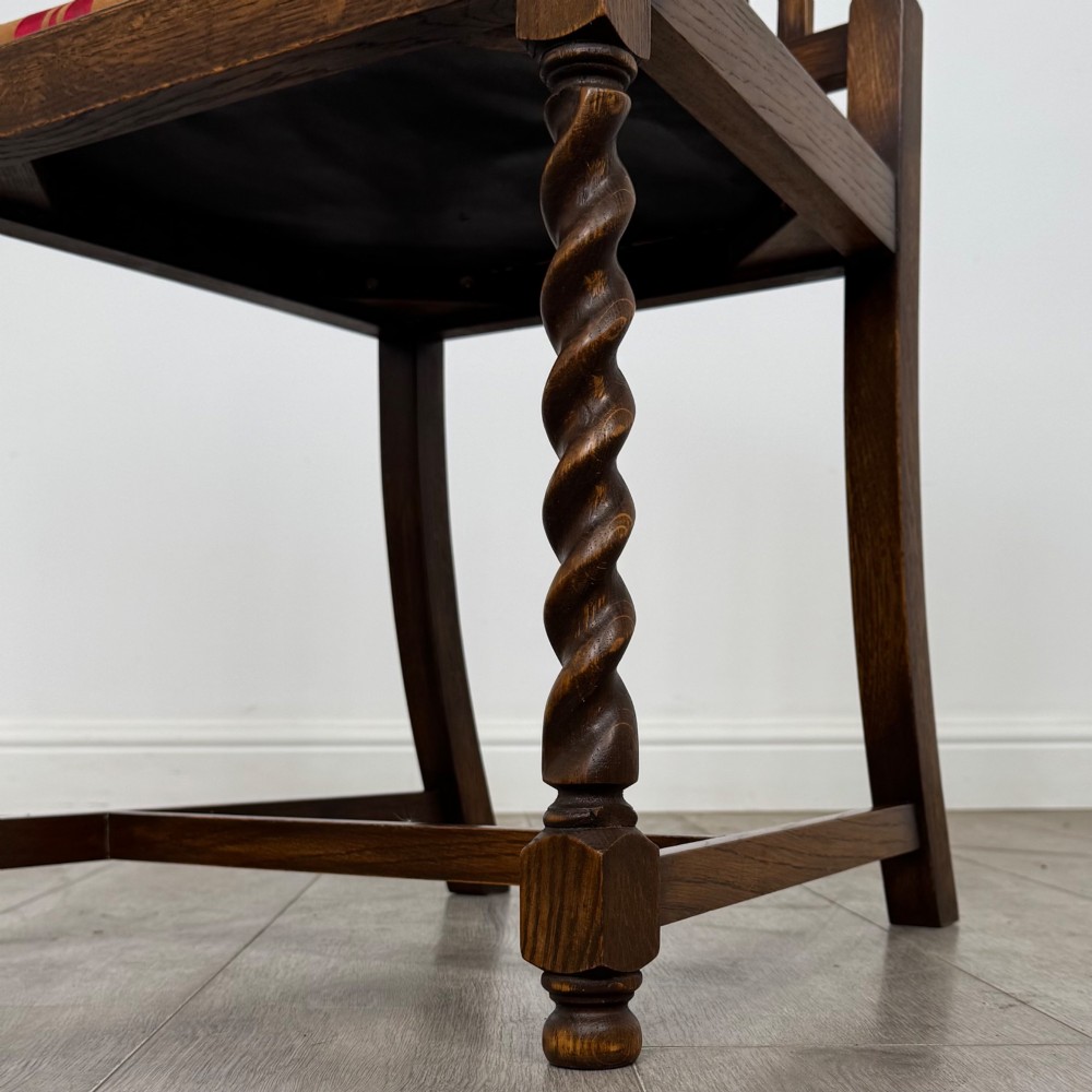 A set of four dark oak dining chairs featuring slatted backrests, barley twist front legs, and red and gold striped upholstered seat pads. View VI