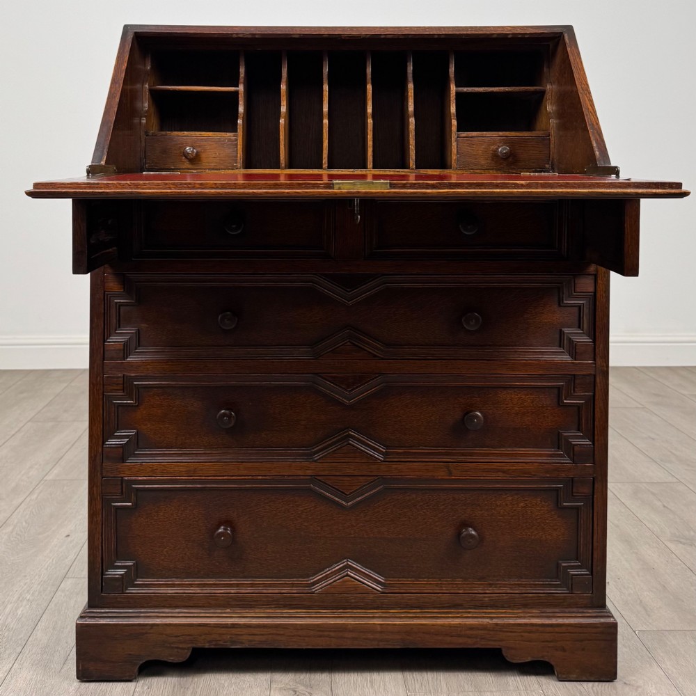 A dark oak Jacobean style slant-front bureau featuring geometric inlaid panels and four drawer fronts with turned wooden knobs. View II