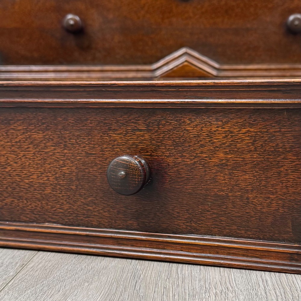 A dark oak Jacobean style slant-front bureau featuring geometric inlaid panels and four drawer fronts with turned wooden knobs. View XIII