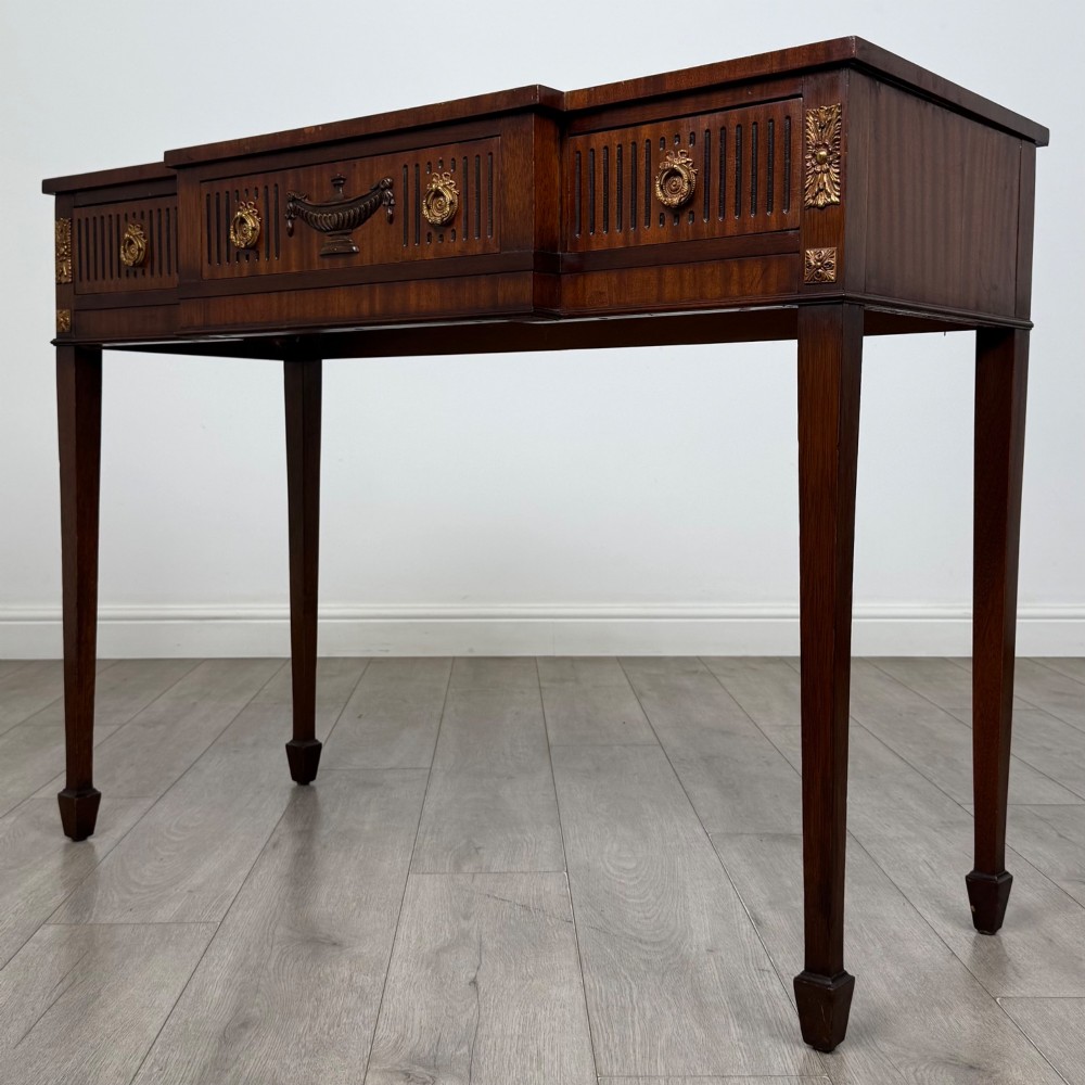 A dark mahogany 20th-century Adam style side table featuring a central carved urn motif, fluted frieze drawers, brass ring handles, and square tapered legs ending in spade feet. View II