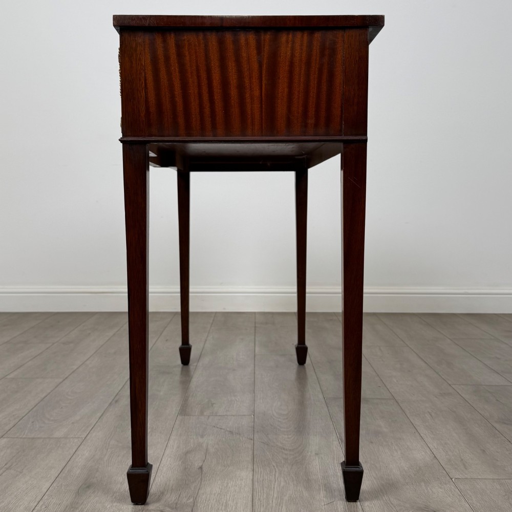 A dark mahogany 20th-century Adam style side table featuring a central carved urn motif, fluted frieze drawers, brass ring handles, and square tapered legs ending in spade feet. View III