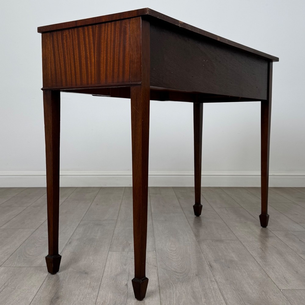 A dark mahogany 20th-century Adam style side table featuring a central carved urn motif, fluted frieze drawers, brass ring handles, and square tapered legs ending in spade feet. View IV
