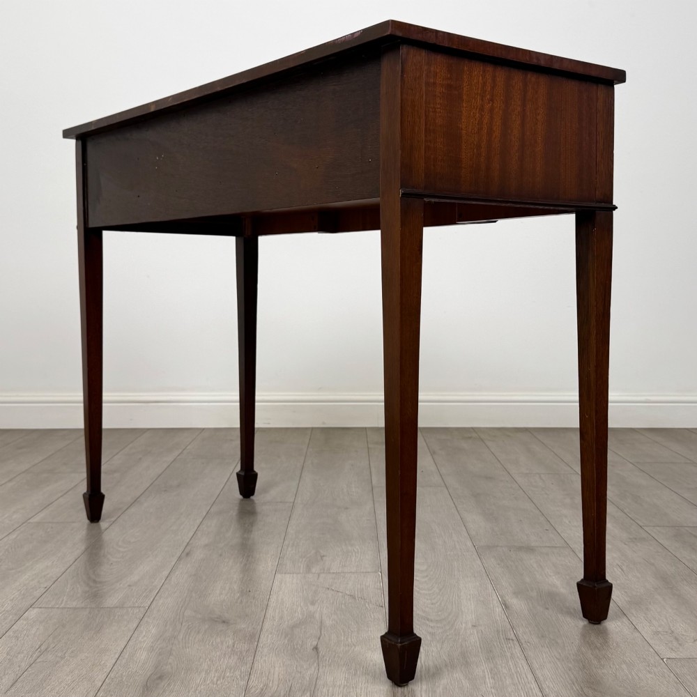 A dark mahogany 20th-century Adam style side table featuring a central carved urn motif, fluted frieze drawers, brass ring handles, and square tapered legs ending in spade feet. View VI