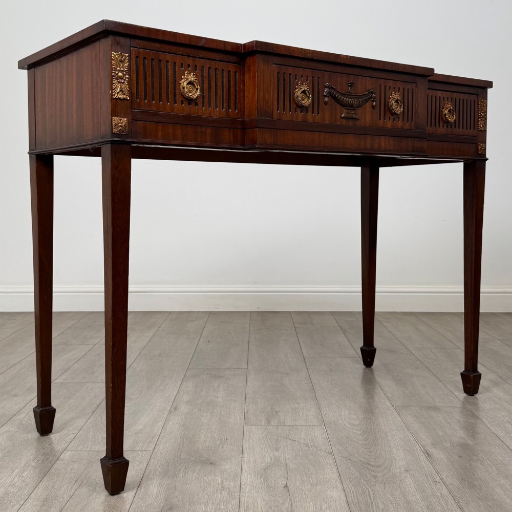 A dark mahogany 20th-century Adam style side table featuring a central carved urn motif, fluted frieze drawers, brass ring handles, and square tapered legs ending in spade feet. View VIII