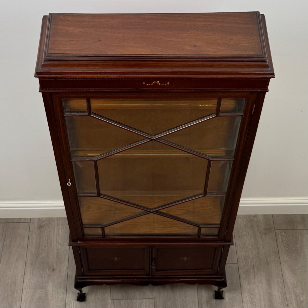 An early 20th-century mahogany glazed display cabinet featuring geometric astragal doors, marquetry inlaid lower cupboards, and cabriole legs. View X