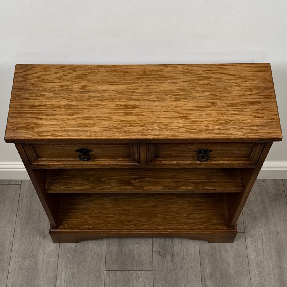 A small 20th-century open oak bookcase featuring two drawers at the top with dark twisted ring handles above two open shelves. View IX