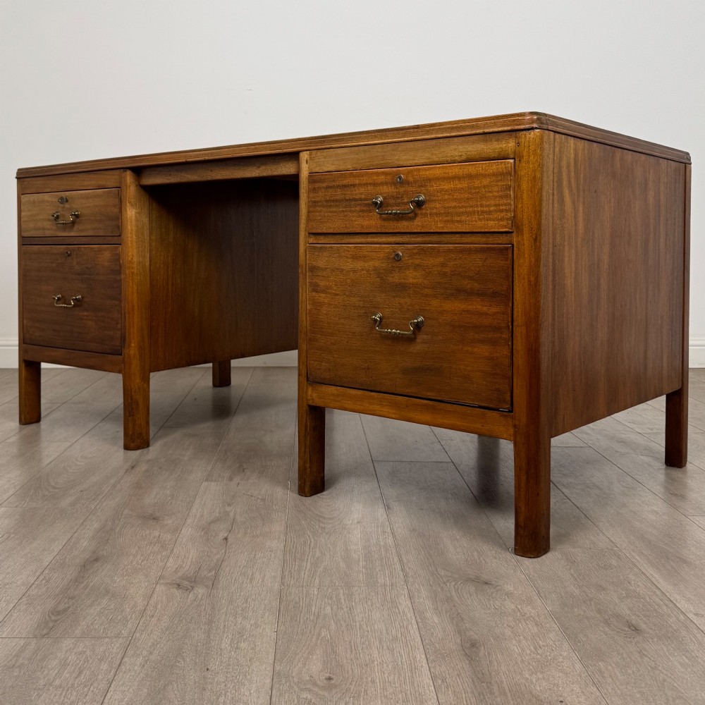 A large mid-20th century mahogany pedestal desk featuring two sets of drawers with brass drop handles and a central kneehole. View II