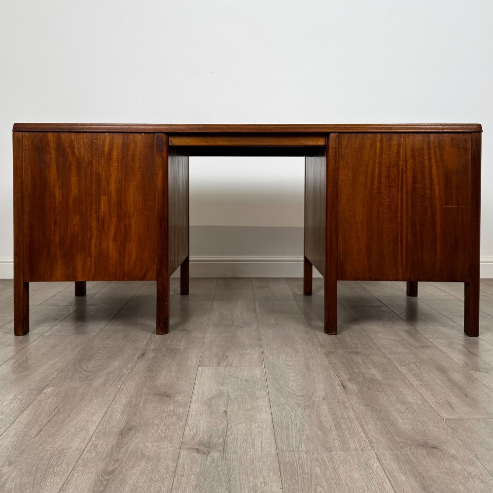 A large mid-20th century mahogany pedestal desk featuring two sets of drawers with brass drop handles and a central kneehole. View V