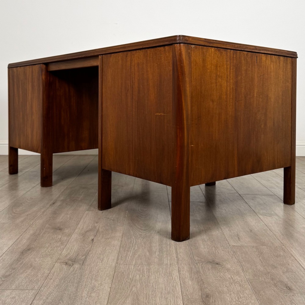 A large mid-20th century mahogany pedestal desk featuring two sets of drawers with brass drop handles and a central kneehole. View VI