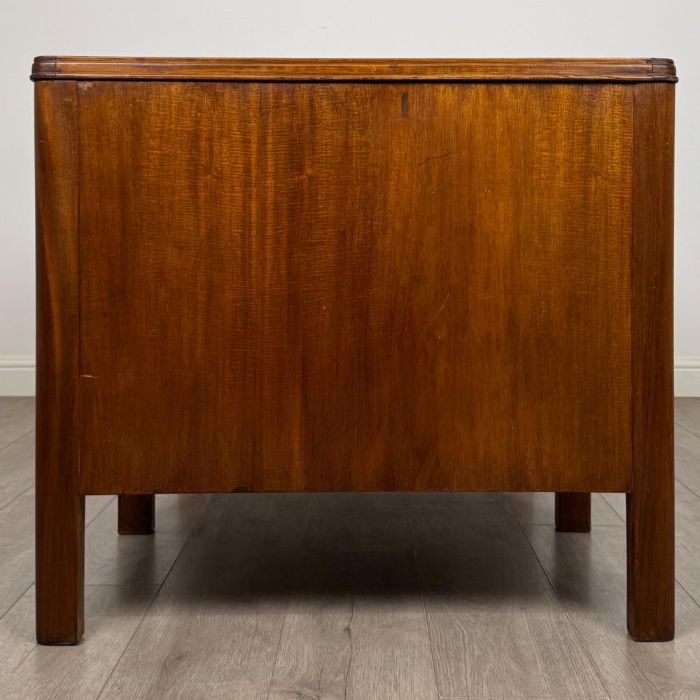 A large mid-20th century mahogany pedestal desk featuring two sets of drawers with brass drop handles and a central kneehole. View VII