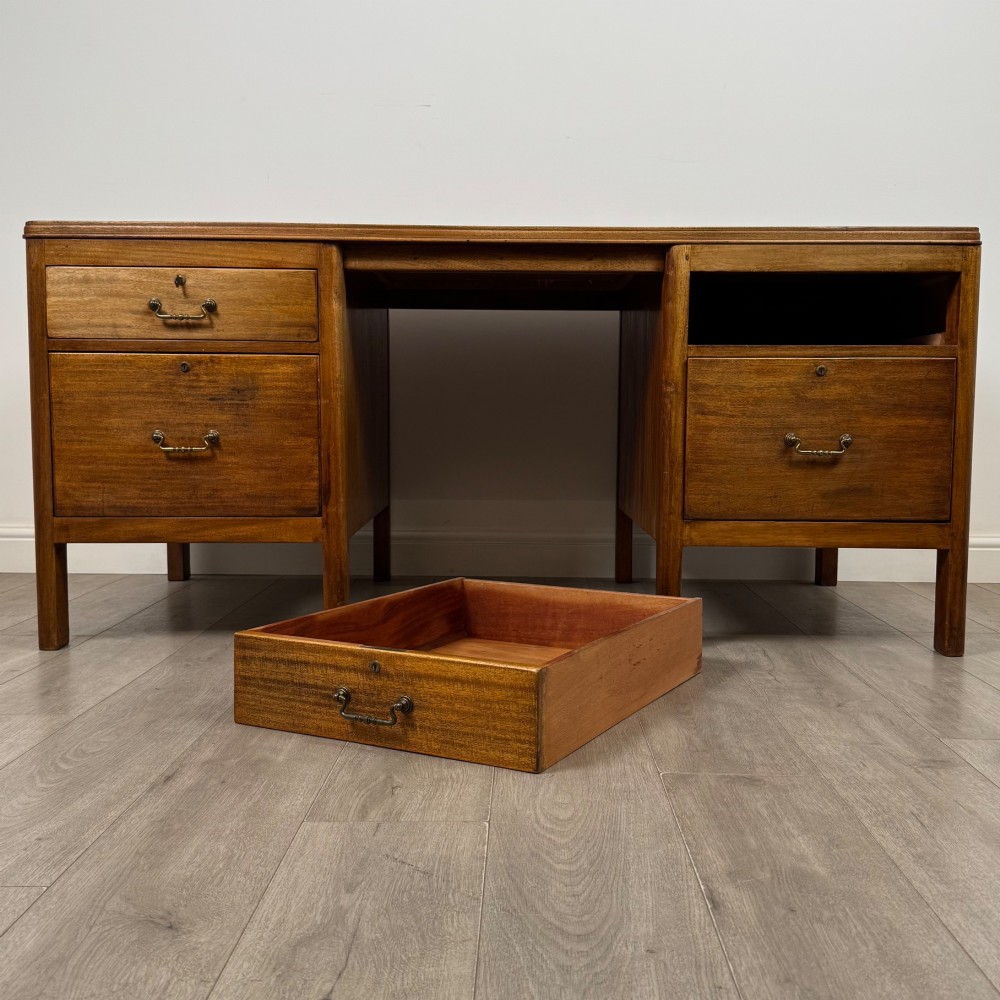 A large mid-20th century mahogany pedestal desk featuring two sets of drawers with brass drop handles and a central kneehole. View X