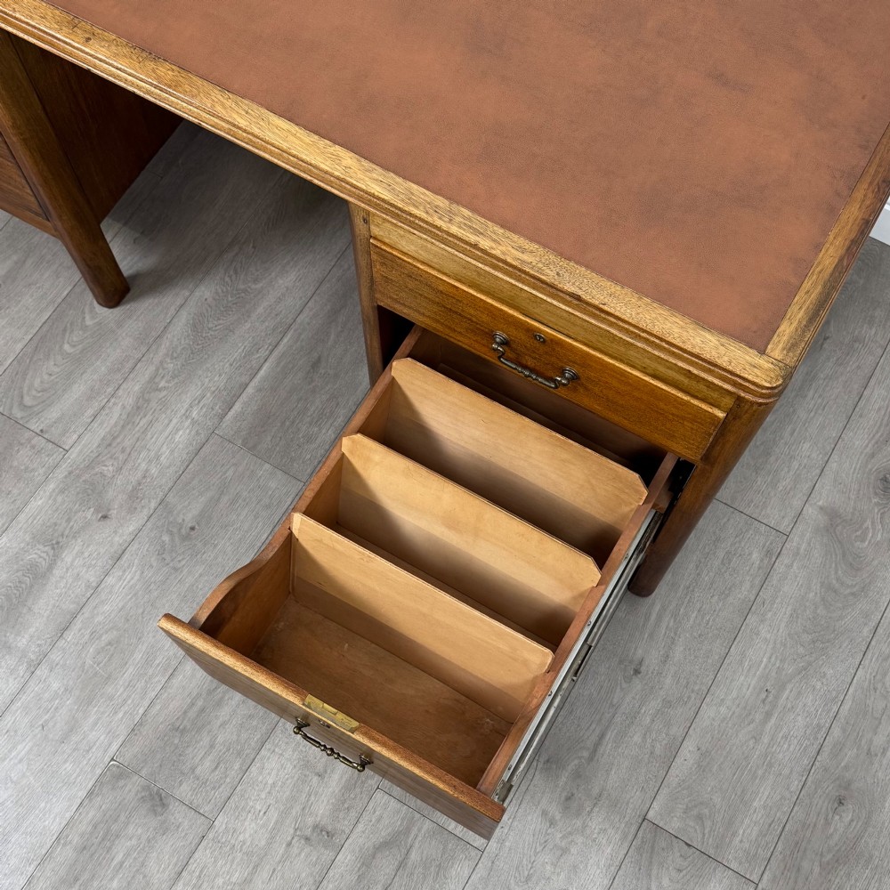 A large mid-20th century mahogany pedestal desk featuring two sets of drawers with brass drop handles and a central kneehole. View XII