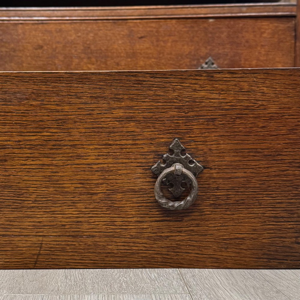A dark oak chest of four drawers decorated with carved floral rosettes and dark metal drop ring handles. View XI