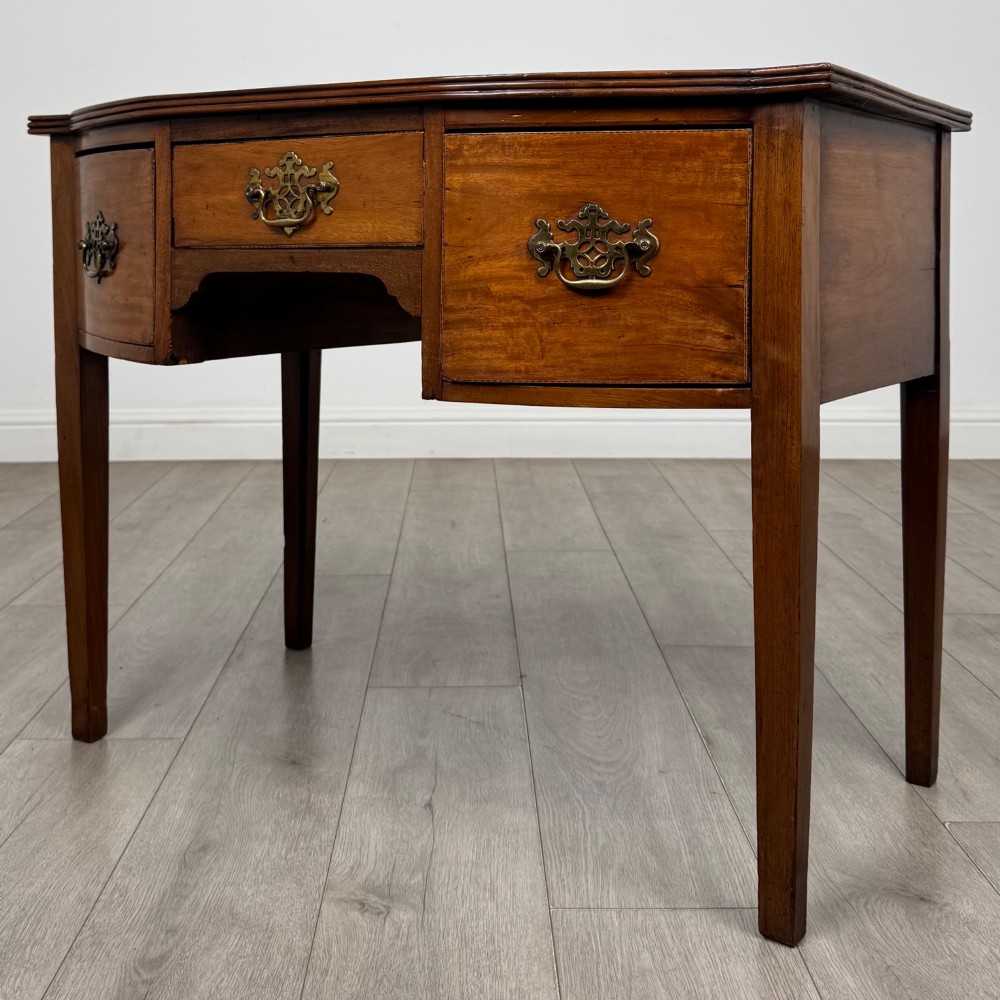 An 18th-century Georgian mahogany writing table with a bow-front top, three drawers fitted with brass handles, supported by square tapered legs. View II