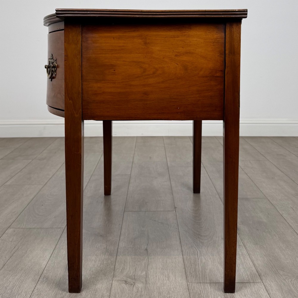 An 18th-century Georgian mahogany writing table with a bow-front top, three drawers fitted with brass handles, supported by square tapered legs. View III