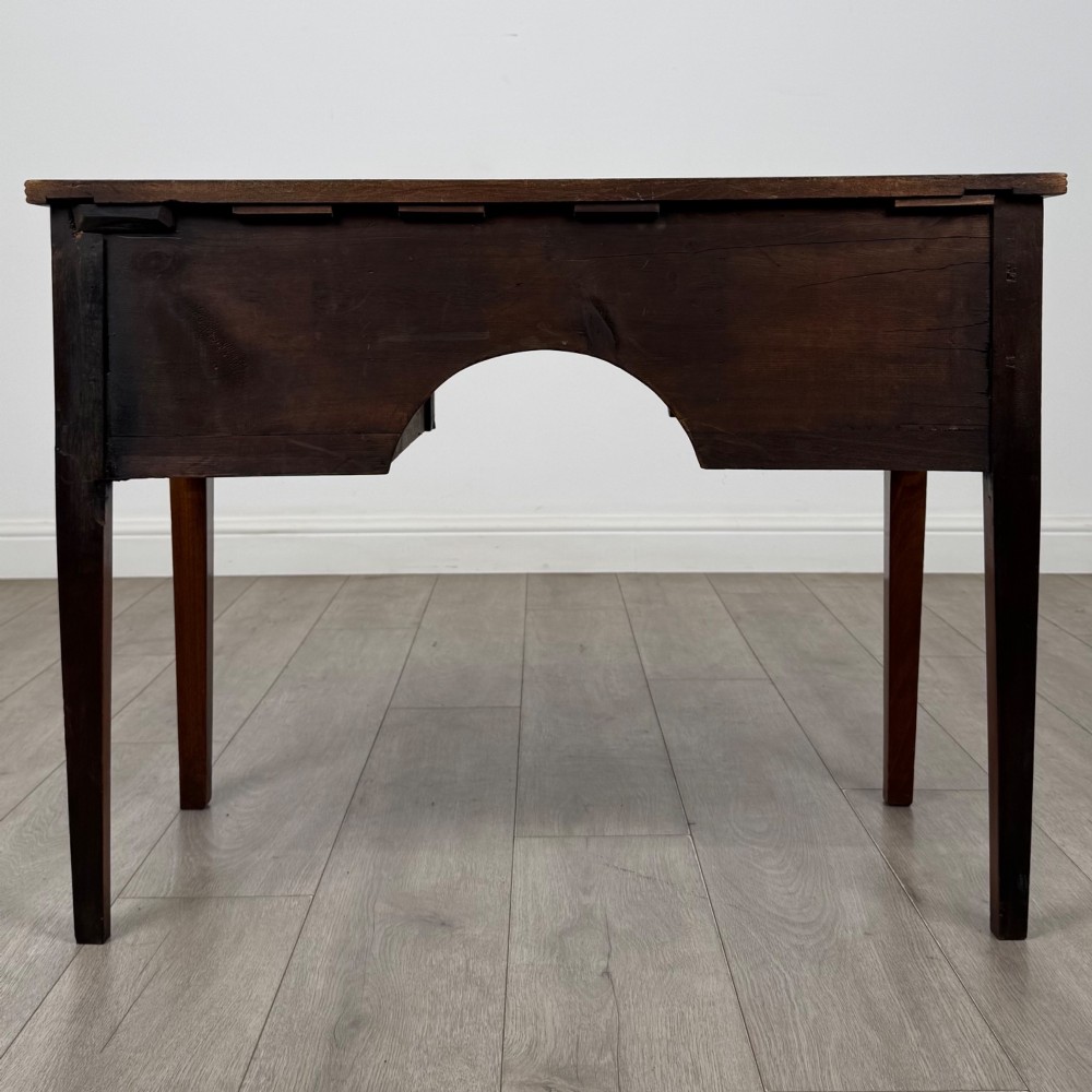 An 18th-century Georgian mahogany writing table with a bow-front top, three drawers fitted with brass handles, supported by square tapered legs. View V