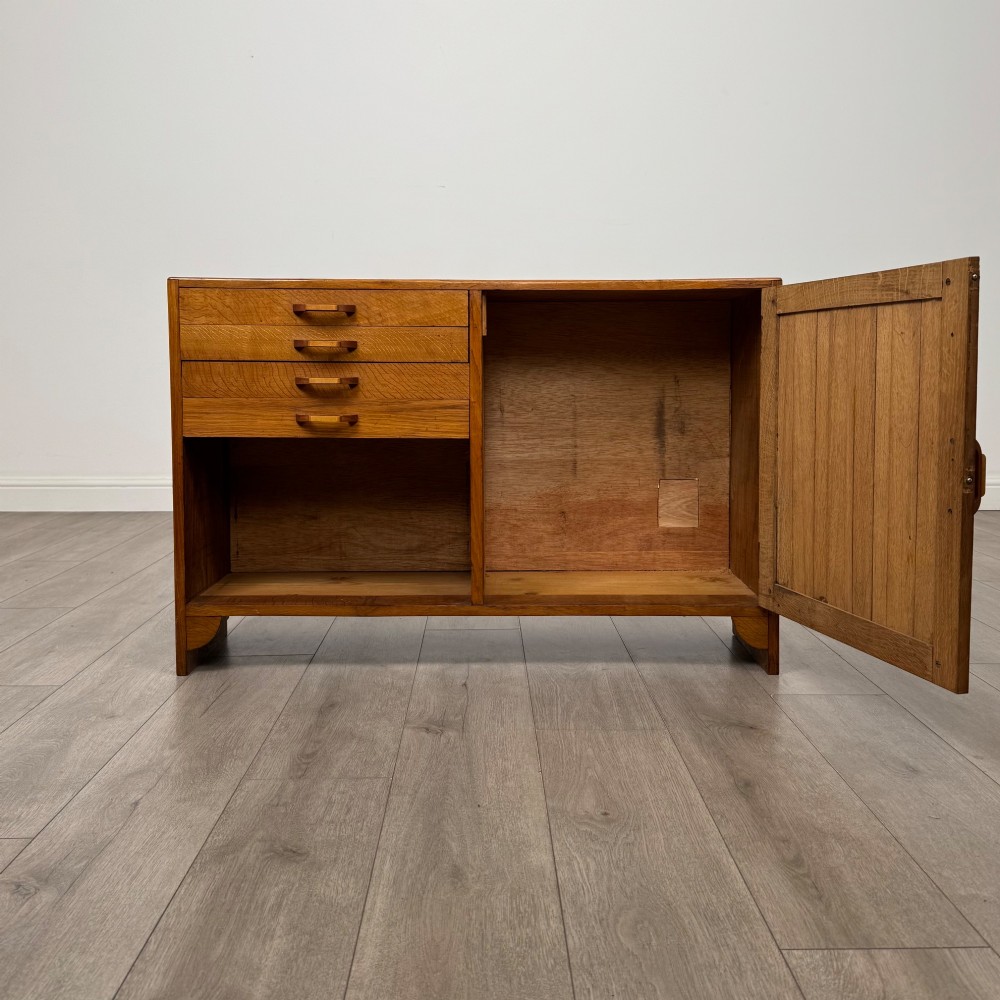 A compact golden oak sideboard featuring four shallow drawers on the left, an open shelf below, and a slatted single door cabinet on the right. View II