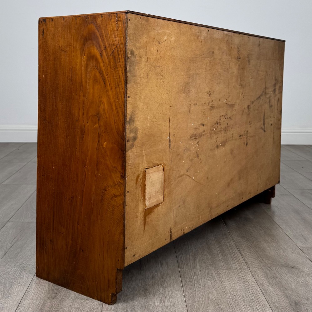 A compact golden oak sideboard featuring four shallow drawers on the left, an open shelf below, and a slatted single door cabinet on the right. View V