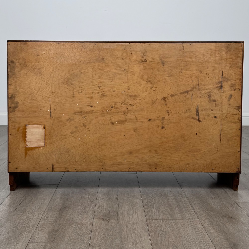 A compact golden oak sideboard featuring four shallow drawers on the left, an open shelf below, and a slatted single door cabinet on the right. View VI