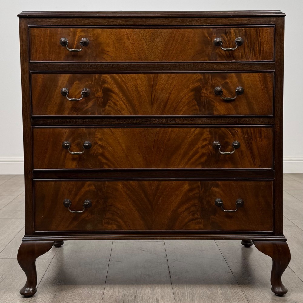 A mahogany chest of drawers featuring four full-width drawers with flame veneer fronts, brass handles, and cabriole legs.