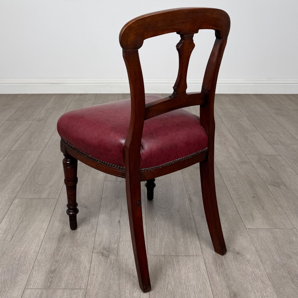 A set of four 19th-century mahogany dining chairs featuring carved open backs, dark red leather upholstered seats with stud trim, and turned front legs. View III