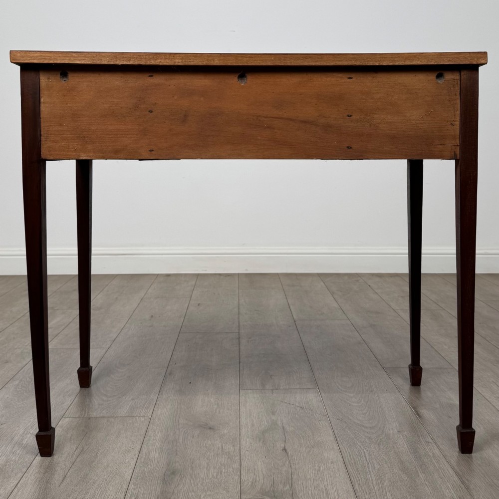 An early 20th-century mahogany writing table featuring three drawers with decorative brass ring handles and square tapered legs. View V