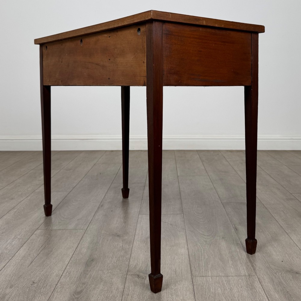 An early 20th-century mahogany writing table featuring three drawers with decorative brass ring handles and square tapered legs. View VI