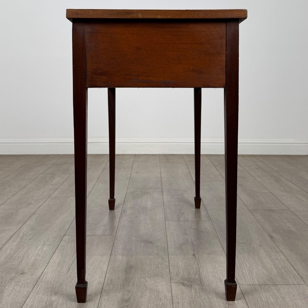 An early 20th-century mahogany writing table featuring three drawers with decorative brass ring handles and square tapered legs. View VII