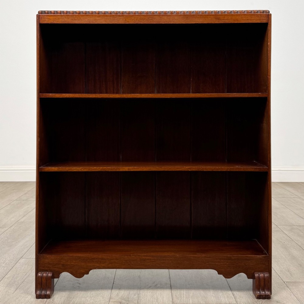 An antique narrow mahogany open bookcase featuring three tiers, a gadrooned top edge, and carved bracket feet. View II