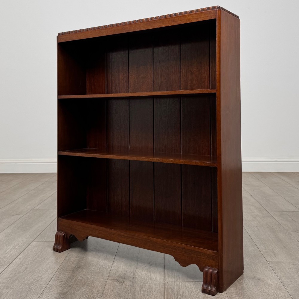 An antique narrow mahogany open bookcase featuring three tiers, a gadrooned top edge, and carved bracket feet. View III
