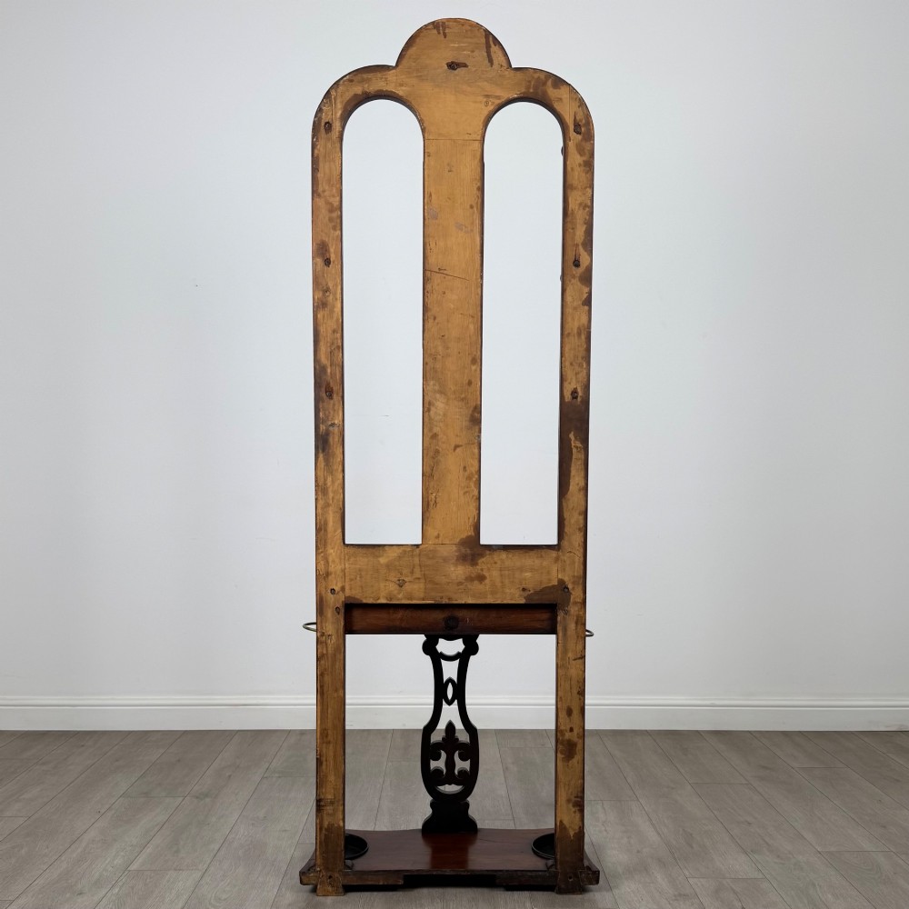 A freestanding Victorian mahogany hall stand featuring turned coat pegs, a narrow central mirror panel, a small shelf, and an umbrella holder base. View V