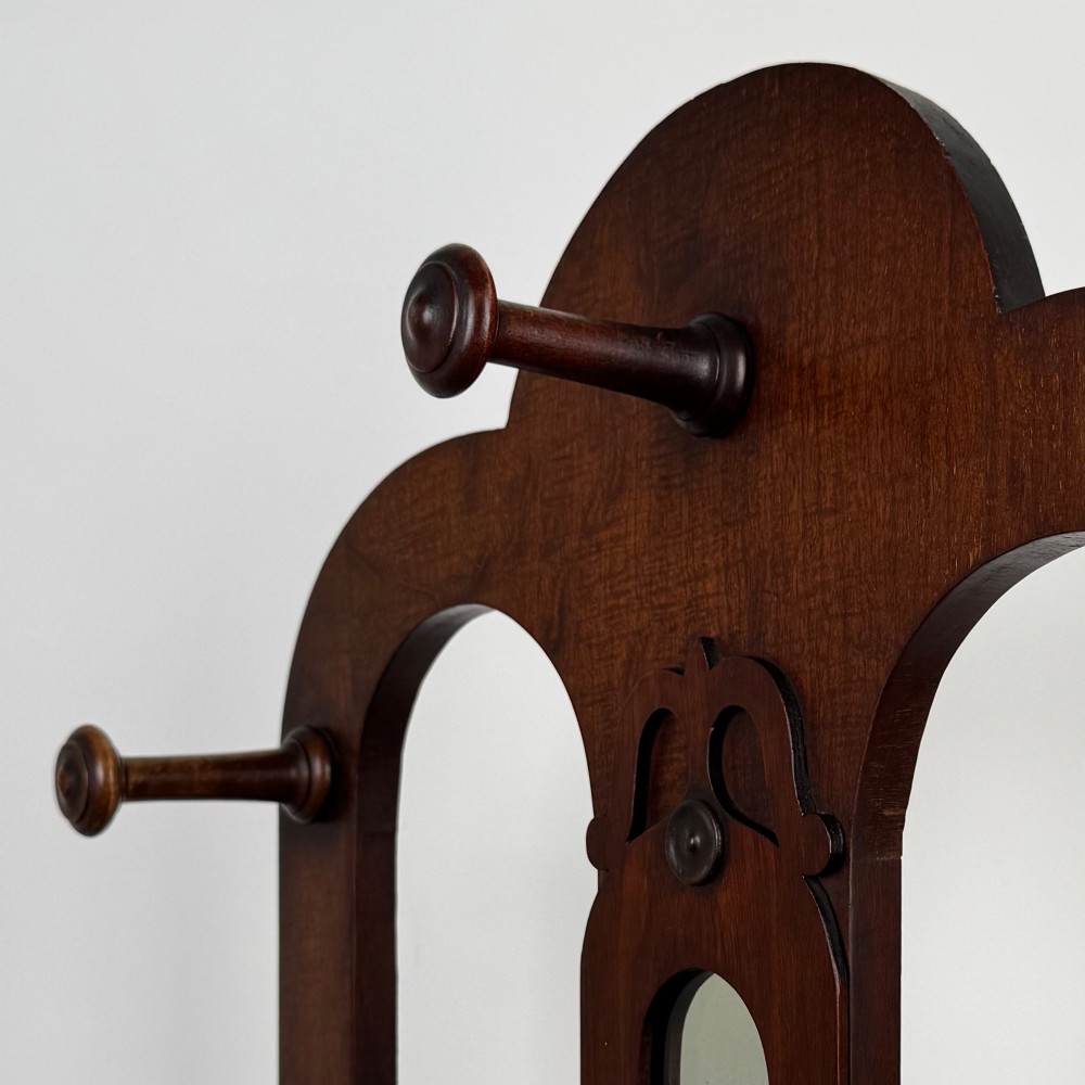 A freestanding Victorian mahogany hall stand featuring turned coat pegs, a narrow central mirror panel, a small shelf, and an umbrella holder base. View XI