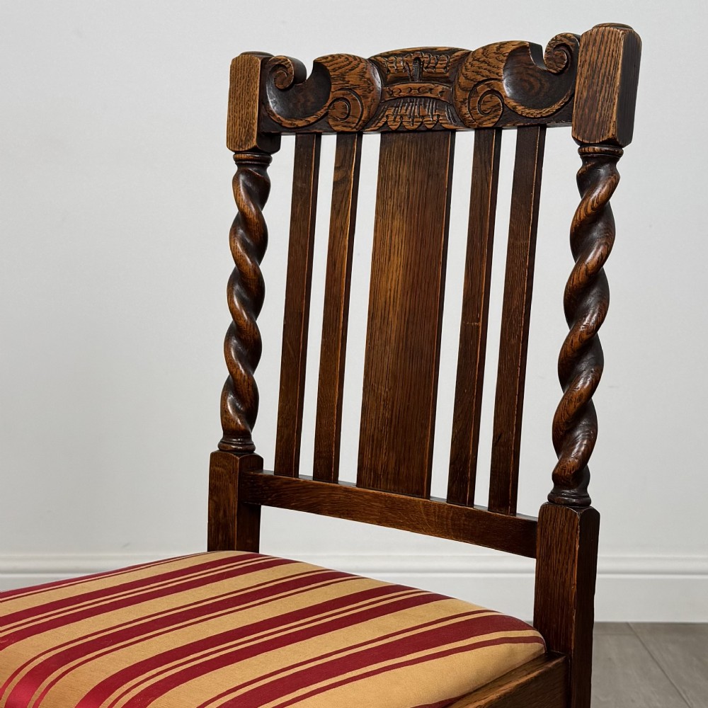 A set of six dark oak dining chairs featuring barley twist legs and stretchers with red and gold striped fabric seats. View V
