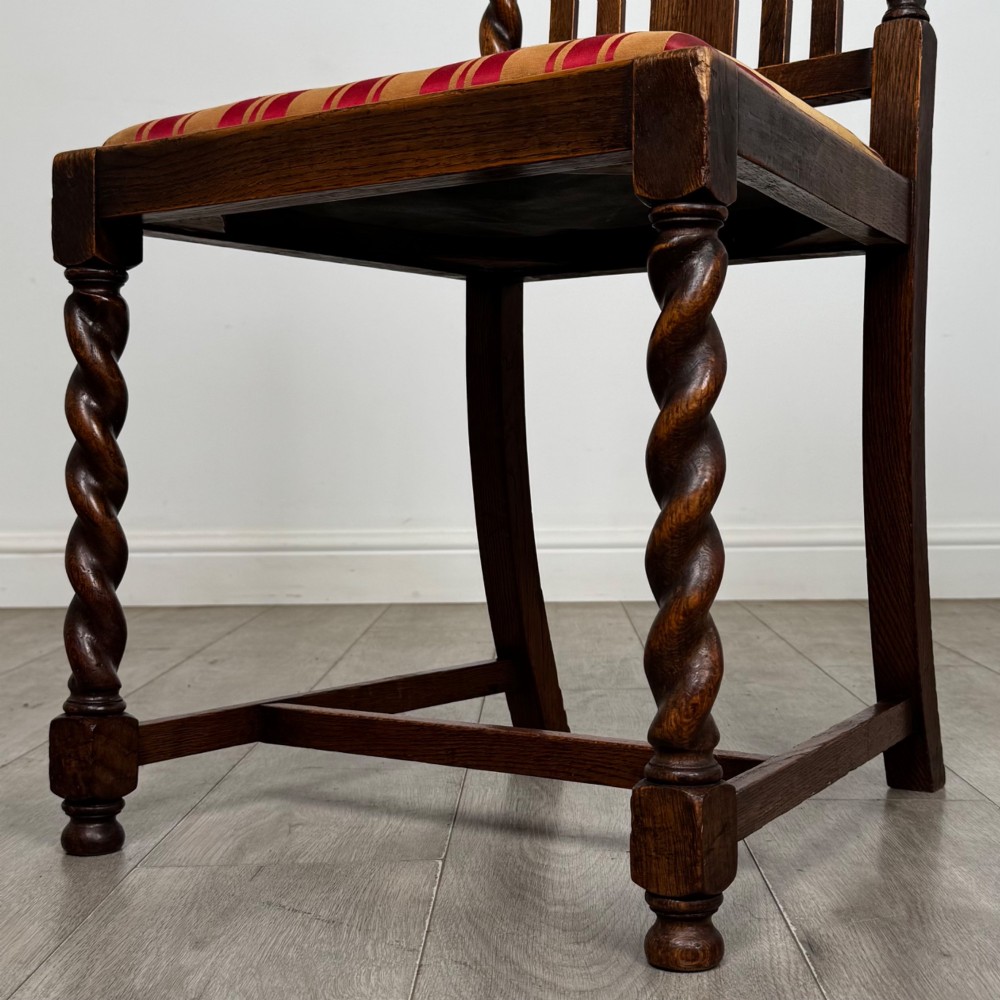 A set of six dark oak dining chairs featuring barley twist legs and stretchers with red and gold striped fabric seats. View VI