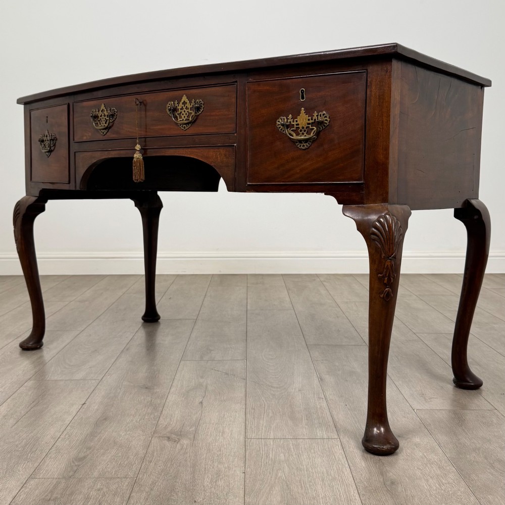An Edwardian mahogany writing table with cabriole legs, carved knee detailing, three drawers with ornate brass handles, and a central arched kneehole. View II
