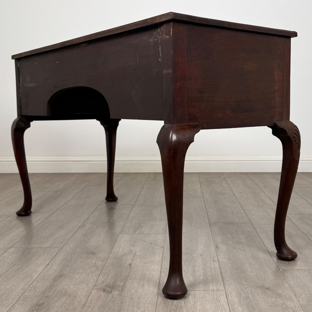 An Edwardian mahogany writing table with cabriole legs, carved knee detailing, three drawers with ornate brass handles, and a central arched kneehole. View VI