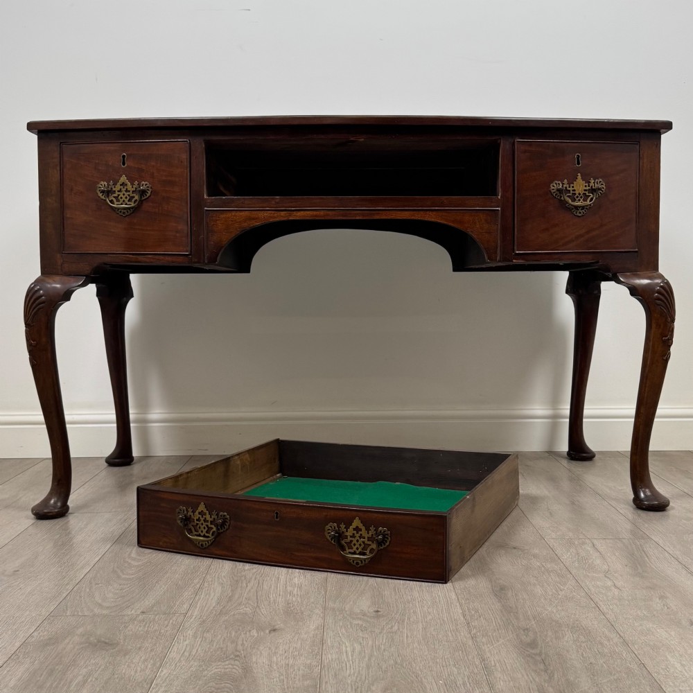 An Edwardian mahogany writing table with cabriole legs, carved knee detailing, three drawers with ornate brass handles, and a central arched kneehole. View X