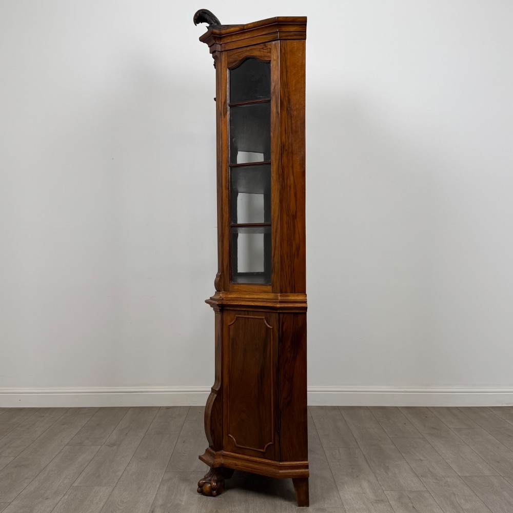A Dutch walnut display cabinet featuring a carved bonnet-top pediment, multi-pane glazed doors, and a lower chest of drawers on carved claw-and-ball feet. View IV