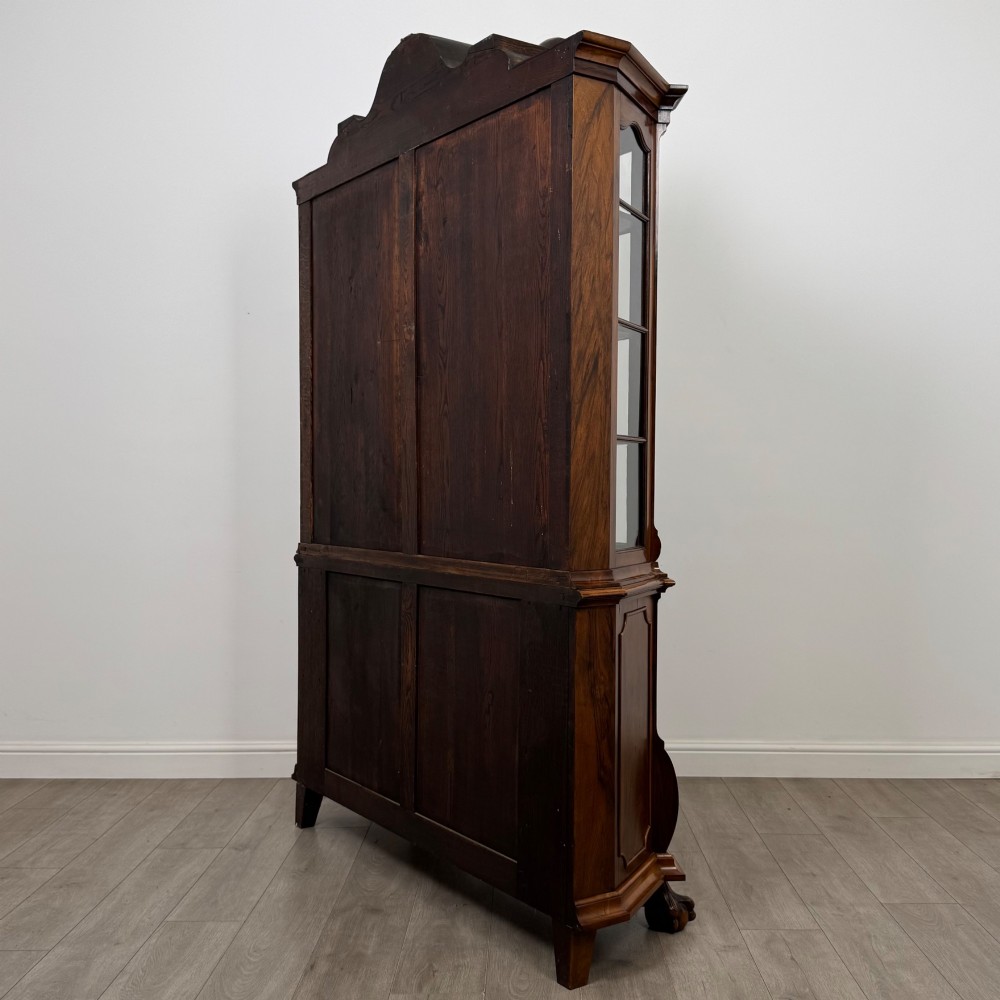 A Dutch walnut display cabinet featuring a carved bonnet-top pediment, multi-pane glazed doors, and a lower chest of drawers on carved claw-and-ball feet. View VII
